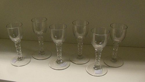 A set of six 18th century wines, each with cylindrical bowls rounding into the facetted stems on cir