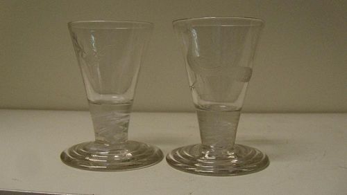 A pair of early 19th century firing glasses, the conical bowls engraved with stags' heads and peacoc