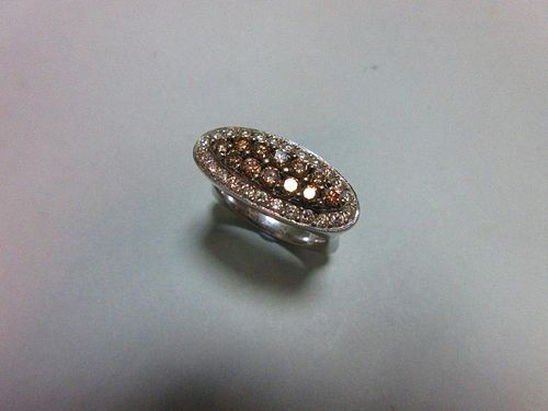 A diamond and coloured diamond pavé set ring, of horizontal elongated oval outline with a central na