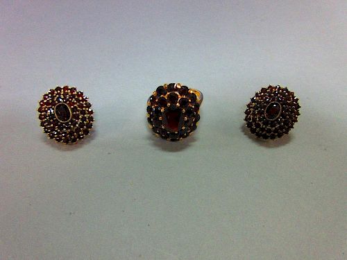 A Bohemian garnet cluster ring and a pair of matched earstuds, the ring with an oval cut pyrope garn