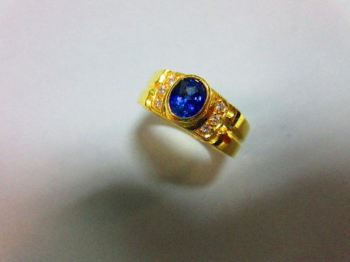 A sapphire and diamond ring, the oval cut intense blue sapphire in a raised collet between lines of