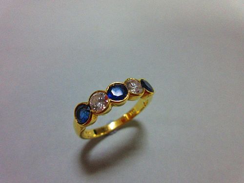 An 18ct gold, sapphire and diamond five stone ring, with two round brilliant cut diamonds spacing th