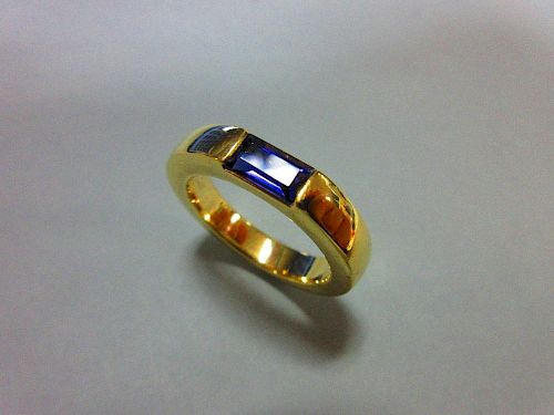 A contemporary iolite ring by Quinn, the rectangular step cut iolite tension set horizontally in a u