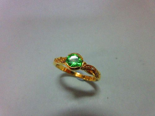 An 18ct gold ring set with a green garnet and diamond highlights, the bright apple green round cut g