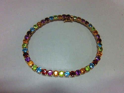 A multi-coloured gem set line bracelet, the uniform round cut gems, to include garnet, blue topaz, p