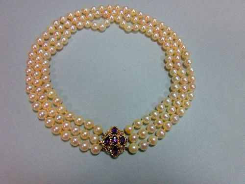 A three row pearl necklace with gold, amethyst and seed pearl clasp, the uniform 7.5-8mm cultured pe