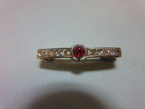 A ruby and diamond pin brooch circa 1930, with a sugarloaf cabochon ruby collet set between lines of