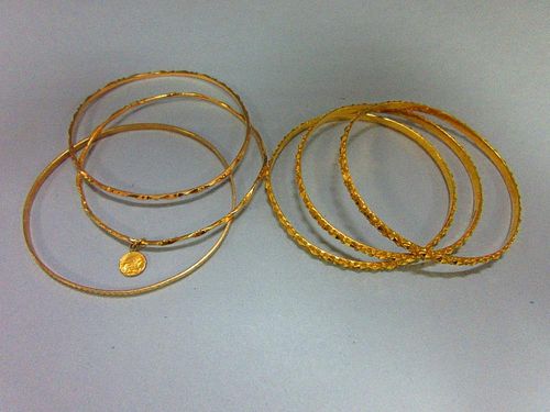 A collection of gold slave bangles, three of hallmarked 22ct gold with faceted diaper patterning, Lo
