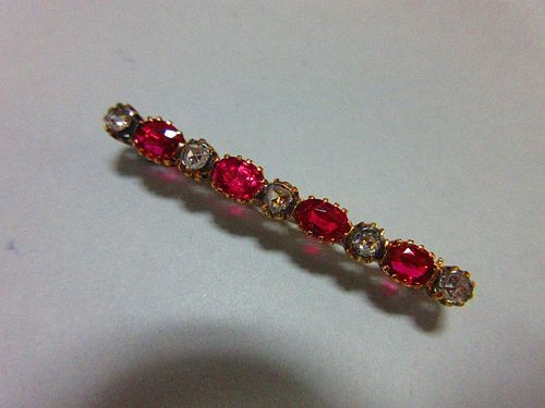 A ruby and diamond brooch, of bar form close set with five rose cut diamonds separated by four oval