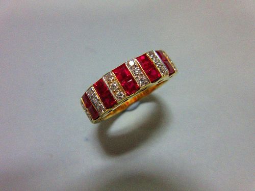 A contemporary 18ct gold ruby and diamond band ring, set all around the front with alternating verti