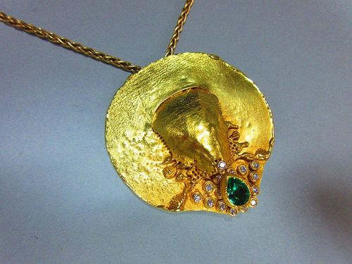 A contemporary emerald and diamond set disc pendant and 18ct gold chain, the variably textured and d