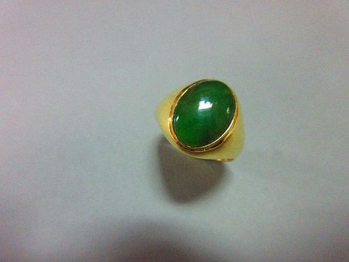 A jade signet form ring, set with a low cabochon polished mid-green jade in rubover setting merging