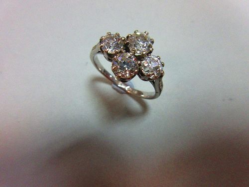 An unusual four stone diamond ring, the old round brilliant cut diamonds claw set in a horizontal di