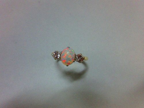 An opal and diamond three stone ring, the oval cabochon opal claw set between two round brilliant cu
