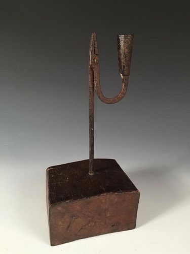 An 18th century iron rushlight holder with later wooden base, the square stem topped by a squared ja