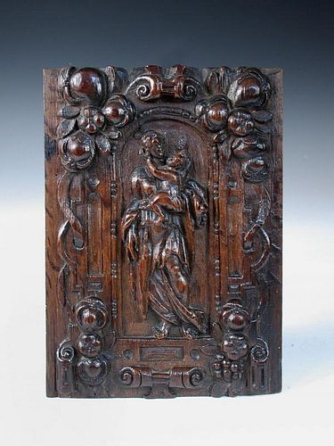 An 18th century North European relief carved oak panel, depicting the Madonna and Child within an ar
