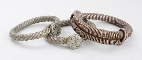 TWO SIMILAR SOLID METAL TWIST BRACELETS WITH DISC JOINTS AND A SPIRAL-RINGED BRACELET