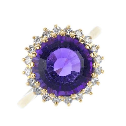 An 18ct gold amethyst and diamond cluster ring. The circular-shape amethyst, within a brilliant-cut