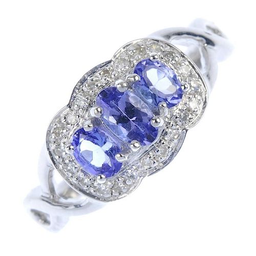 A 9ct gold tanzanite and diamond dress ring. The graduated oval-shape tanzanite line, within a singl