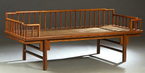 Chinese Carved Elm Daybed, 20th c., with three arched spindled rail sides, over a rattan seat, on cylindrical legs joined by cylindrical stretchers, H
