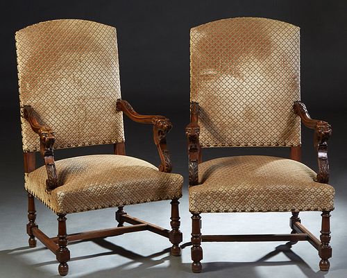 Pair of French Louis XIV Style Carved Walnut Fauteuils, late 19th c., the arched canted cushion back over lion carved curved arms, to a cushioned seat