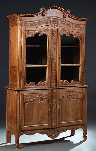 French Provincial Carved Pine Buffet a Deux Corps, 19th c., the arched stepped scrolled crown over two mullioned glazed doors with iron fiche inches a