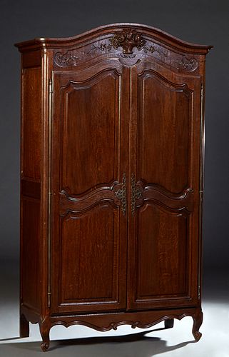 French Provincial Louis XV Style Carved Oak Armoire, 19th c., the arched stepped crown over a central relief carved floral basket, above double two pa