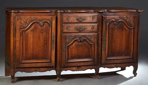 French Provincial Louis XV Style Carved Oak Sideboard, late 19th c., the stepped rounded edge serpentine top over a bank of two drawers above a fielde