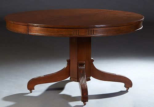 American Classical Carved Mahogany Dining Table, 19th c., the circular top over a wide skirt, on a hexagonal support with reeded arched legs on caster