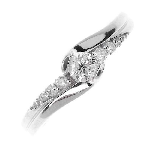 A diamond single-stone ring. The brilliant-cut diamond, to the similarly-cut diamond sides. Estimate