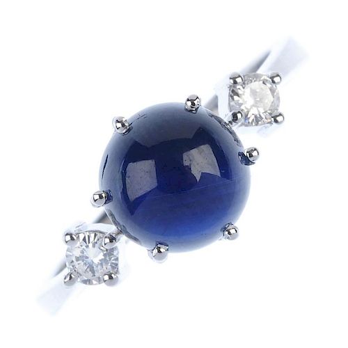 A sapphire and diamond three-stone ring. The circular sapphire cabochon, to the brilliant-cut diamon