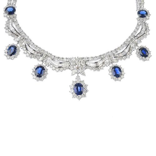 A sapphire and diamond necklace. The graduated oval-shape sapphire and brilliant-cut diamond cluster