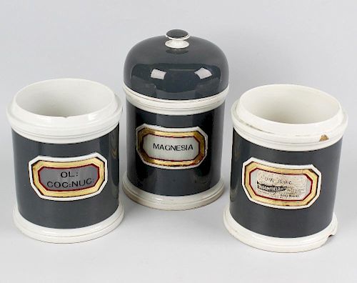 Seven late Victorian pottery apothecary jars, each of cylindrical form with dark green glazed ground