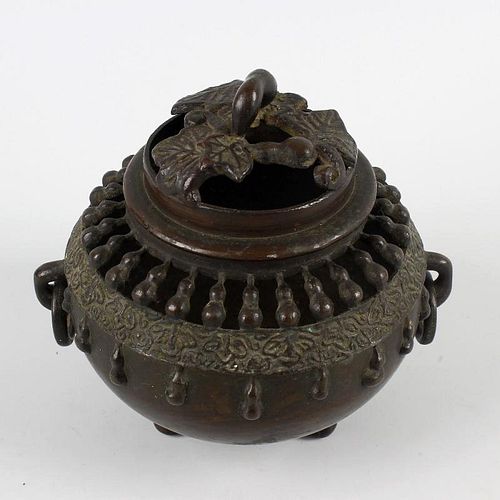 An Oriental bronze koro or incense burner and cover. Of spherical form with pierced domed foliate co