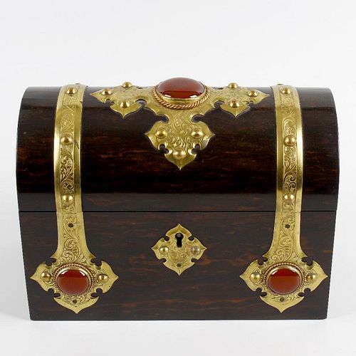 A coromandel box. Having foliate engraved brass strap work and fittings set with large red cabochons