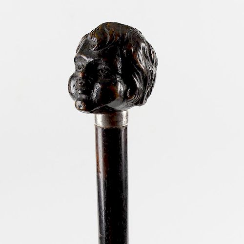 An unusual ebonised walking stick or cane. The handle carved as the head of a child, on engraved met