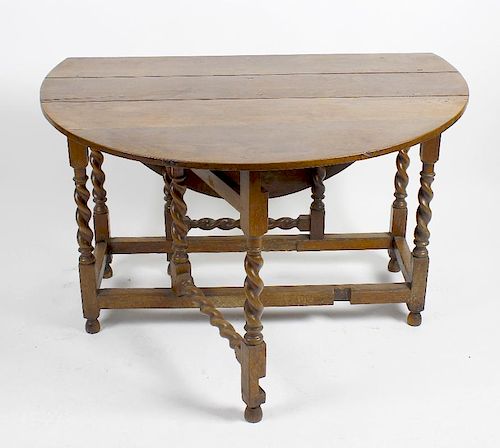 An oak drop leaf gateleg table. The oval top above single frieze drawer and false drawer, raised upo