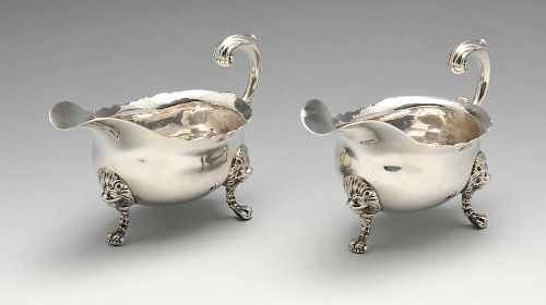 A pair of George III silver sauce boats, the oval form raised on three lion mask paw feet, rising to