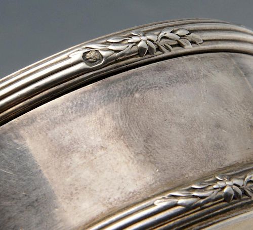 A French silver box of circular form with reeded borders and floral spray accents, the hinged cover