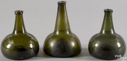 Three blown olive glass squat bottles, late 18th c., 6 1/2'' h., 7 3/4'' h., and 6 3/4'' h.