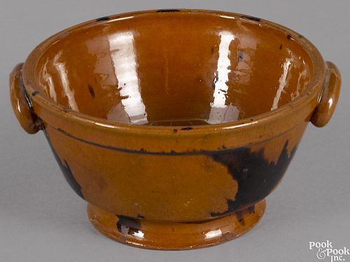 Pennsylvania redware footed bowl, 19th c., with manganese splotches and applied ram's horn handles