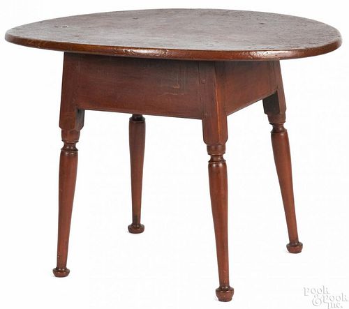 Painted pine tavern table with an oval top and a red surface, 25'' h., 35 1/2'' w.