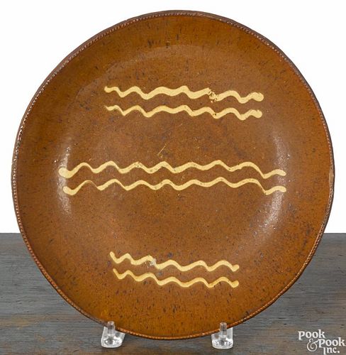 Large redware shallow bowl, 19th c., with yellow slip and speckled manganese decoration