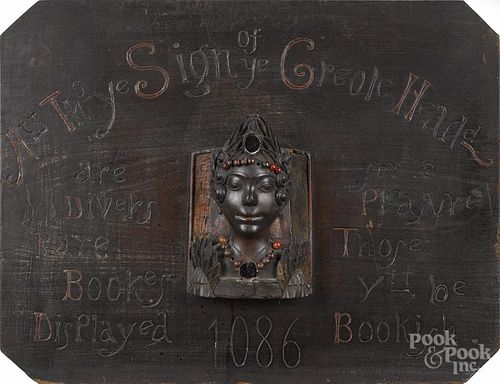 Carved pine Bookstore trade sign, late 19th c., with relief mask of a Creole woman