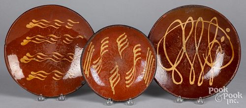 Three slip decorated redware plates, 19th c.