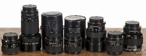 Seven Canon camera lenses, 24mm to 200mm, FD mounts,  two with cases.
