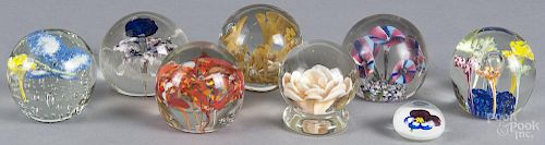 Eight glass paperweights with floral decoration, designs to include a rose, trumpet flowers