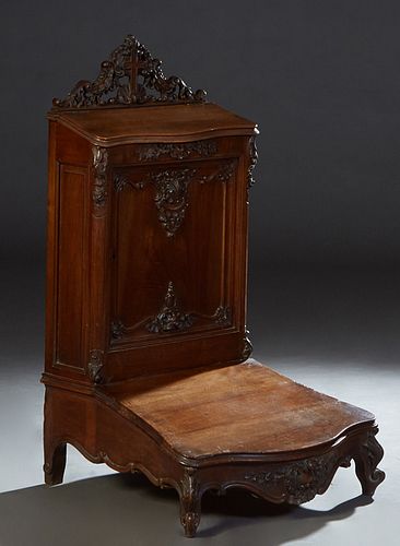 French Provincial Carved Walnut Louis XV Style Prie Dieu, 19th c., with a pierced cruciform crest over a slant top lifting armrest opening to open sto