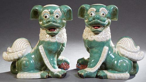 Pair of Large Green and White Glazed Terracotta Seated Foo Dogs, 20th c., each with one paw on an orb, H.- 17 in., W.- 16 in., D.- 11 in. Provenance: 