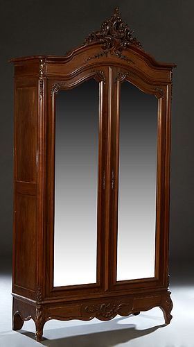 French Carved Mahogany Louis XV Style Armoire, early 20th c., with a floral and leaf carved crest above a stepped arched crown over double arched wide